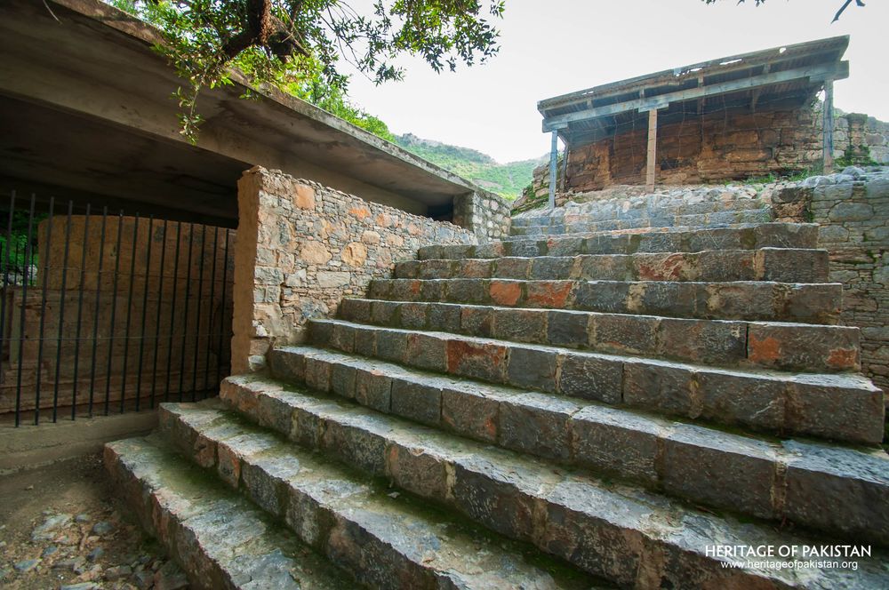 Protected stairway with weathered stone and mountain backdrop